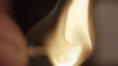 A close-up shot of a blurry horizontal burning matchstick that slowly goes into focus against a blurred background