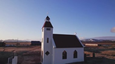 A drone shot showing the Modrudalur church with red roof on a field during daytime in Iceland