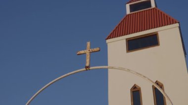 A low-angle shot of a cross at the arch entrance in front of Modrudalur Church in Iceland