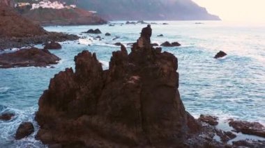 Drone tilting and moving towards the sea stack and showing the coastal landscape of Benijo beach in Tenerife, Spain during daytime