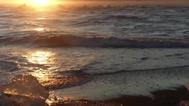 Icebergs floating on and near the coast of Diamond Beach under a lovely sunset