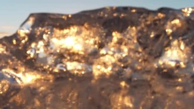 A close-up of an iceberg chunk reflecting the sun's gleaming golden rays