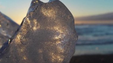 A small iceberg sparkles from the light of the setting sun on the shore of Diamond Beach