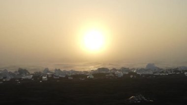 Diamond Beach's black sand with ice blocks against a yellow sunset with a beautiful seascape in the background