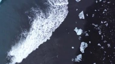 Aerial top view footage of sea waves crashing on the icebergs on the coast of Diamond Beach