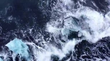 Aerial view of giant waves crashing onto the iceberg fragments of Diamond Beach