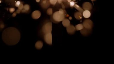 Yavaş çekimde bokeh ışıklandırma efektleriyle yanan maytap çubuğunun yakın çekim görüntüsü