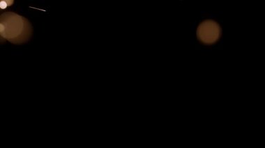 Blurred bokeh lighting effects from burning sparklers on the left side of the frame in slow motion