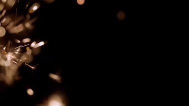 Blurred bokeh lighting effects from burning sparklers on the left side of the frame in slow motion