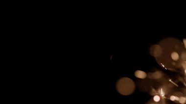 Blurred bokeh lighting effects from burning sparklers from the lower side of the frame in slow motion