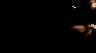 Blurred bokeh lighting effects from burning sparklers from the right side of the frame in slow motion