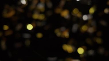 Blurry footage of gold and silver confetting falling against a black background