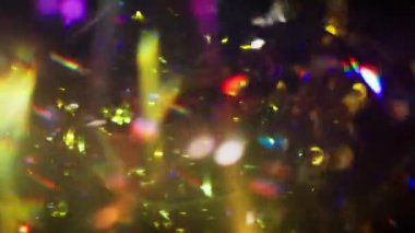 A shower of shiny confetti with lens flare on a black background
