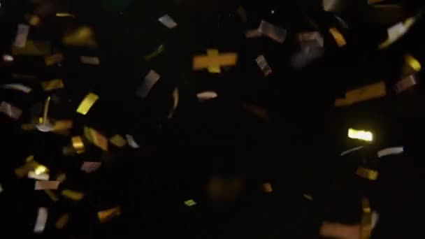 黒の背景に緑のライトの下に落ちる銀と金の色のコンフェッティ — ストック動画