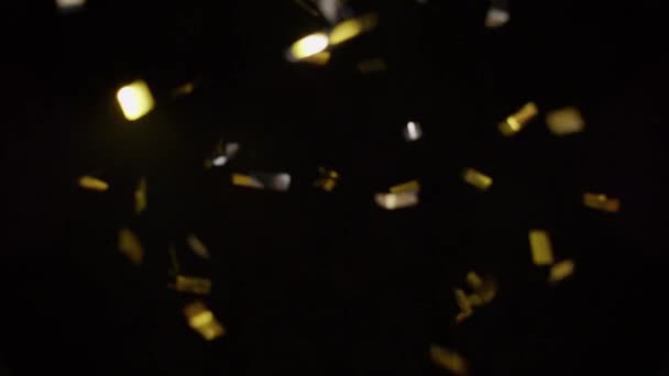 Gold Und Silberkonfetti Leuchtet Licht Und Fällt Vor Schwarzem Hintergrund — Stockvideo