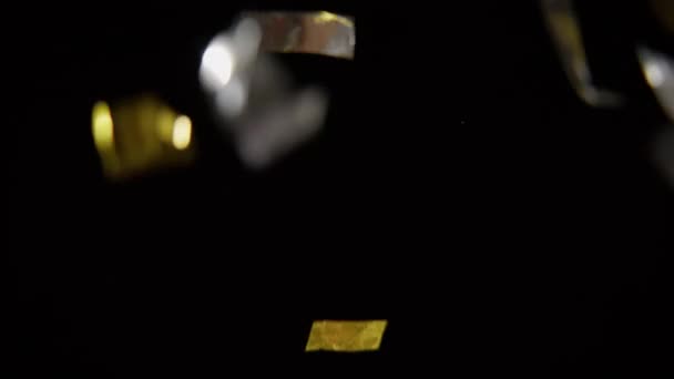 Silberne Und Goldene Konfettibänder Fallen Auf Schwarzem Hintergrund — Stockvideo