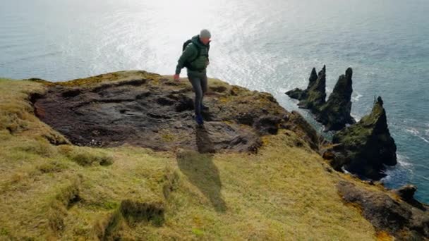 Video Showing Man Walking Precipice Cliff Looks Reynisdrangar Sea Stacks — стоковое видео