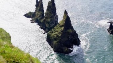 Reynisdrangar deniz yığınlarını ve kuşların İzlanda 'da gündüz uçuşunu gösteren bir hava görüntüsü.