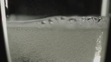 Yakın plan şampanya kabarcıkları yavaşça bir şarap kadehinin içinden yükseliyor.