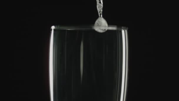 暗い背景を背景にスローモーションでワイングラスに注ぐシャンパンのクローズアップショット — ストック動画