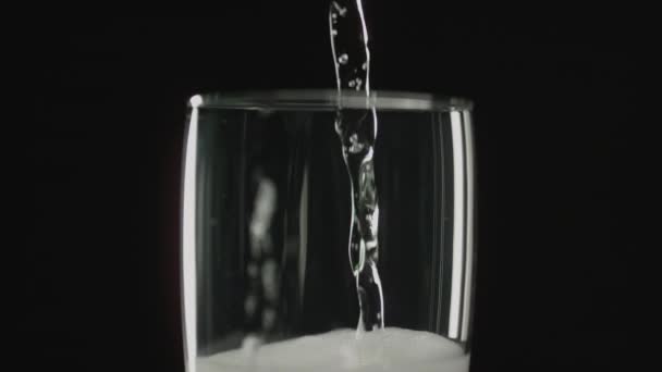 シャンパンが暗い背景を背景にスローモーションで注がれている間に ワイングラスに形成された泡のクローズアップショット — ストック動画