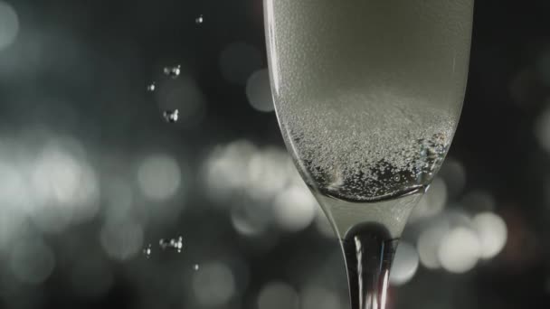 用香槟酒装的长笛杯拍摄的特写镜头 在黑暗的背景下 水滴缓缓地落在左边 — 图库视频影像