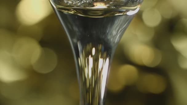 用长笛杯柄拍摄的特写镜头 玻璃杯上的香槟酒泡在酒壶边缓缓旋转 与酒壶的背景相对照 — 图库视频影像