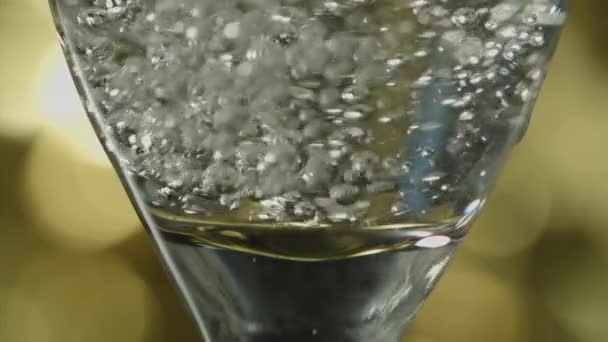 シャンパンで満たされたボウルの底部分のフルートガラスのクローズアップショットは ゆっくりと ボケの背景を背景に — ストック動画