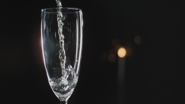 靠近镜头的长笛酒杯 香槟缓缓倒入 背景漆黑 灯光闪烁 — 图库视频影像