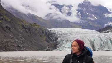 Pan, Svinafellsjokull buzulunu, dağ sırasını ve Skaftafell, İzlanda 'da gündüz vakti ona karşı duran bir adamı göstererek soldan sağa hareket ediyor.