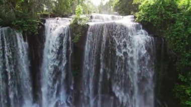 Eğik çekim aşağı doğru hareket ederken Phnom Kulen şelalesinin gündüz saatlerinde insansız hava aracının görüntüsüne sıçradığını gösteriyor.