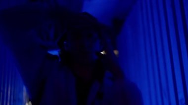 Bir dansçının ritmik kol hareketleri yaparken ve mavi ışıklı bir sokakta poz verirken yakın çekim yavaş çekim görüntüleri.