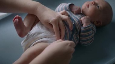 Evdeki bir masanın üstünde bezini değiştiren bir bebeğin yakın çekimi.