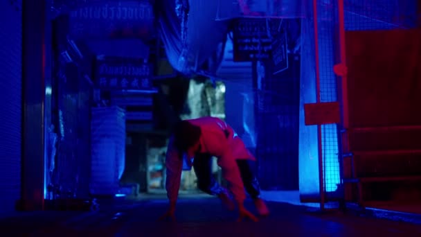 夜にバンコクの路地でフリースタイルのブレイクダンスの動きを行う男のスローモーションショット — ストック動画