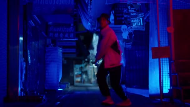 青い光の路地をゆっくりと動き回る現代のストリートダンスをしている男 — ストック動画