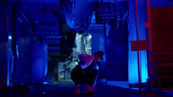 青いライトの路地をゆっくりと動き回るフロアベースのパワーを練習しているストリートダンサー — ストック動画