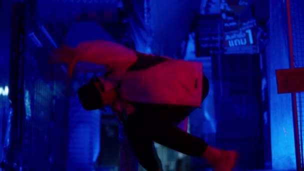 青いライトの路地の床の上でブレイクダンスルーチンを実行している男のスローモーション映像 — ストック動画