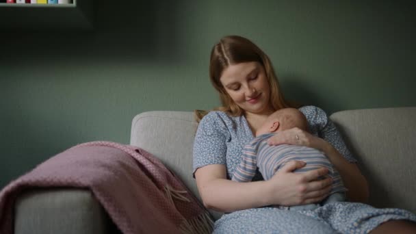 一位母亲一边微笑着一边抚摩睡着的婴儿的背脊 她拥抱在家里的胳膊上 — 图库视频影像