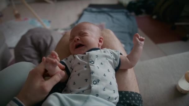 家でソファの上で彼の膝の上に休んで泣いて赤ちゃんを落ち着かせようとしている父親のトップビュー — ストック動画