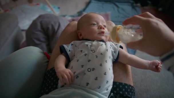 彼の膝の上に眠っている彼の赤ちゃんにミルクを供給父親のトップビューのショット — ストック動画