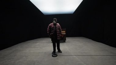 Kamera yavaşça ekose gömlekli bir vokaliste zum yapıyor, arkasında piyano çalan başka bir adamı gösteriyor.