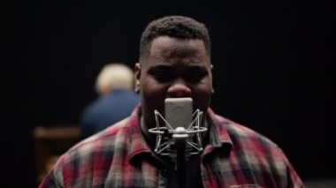 Kamera, arka planda bir piyanist çalarken şarkı söyleyen bir adamın yakın plan çekiminden uzaklaşır.