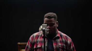 Kamera, ekose gömlekli bir şarkıcıdan uzaklaşır. Stüdyoda bir piyanistin arka planına karşı mikrofonun yanında durur.