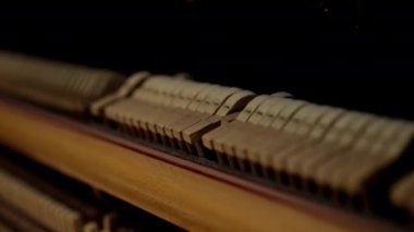 Piyano çekiçleri bir piyanonun içinden yakın plan çekimde tellere vuruyor.