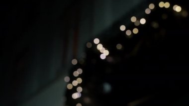 Gece vakti Bokeh 'in Noel ışıklarını çelenk üzerinde göstererek soldan sağa hareket eden çekimler.