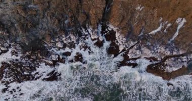 İzlanda 'da gün batımında kayalara çarpan köpüklü dalgaların hava manzarası