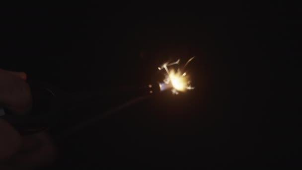 暗い背景に手で照らされている輝きの棒のクローズアップ — ストック動画