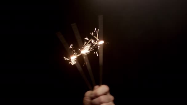 暗い背景を背景にフレームの左側から現れる3つの燃える輝きを上げる手 — ストック動画