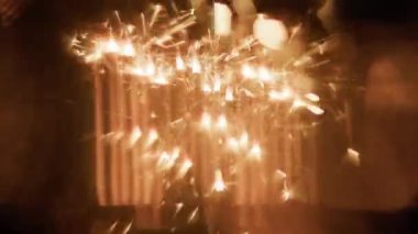 Yanan kıvılcımlar, koyu arkaplana karşı bulanık altın dikey ışık efektleri yayarak hizalanır