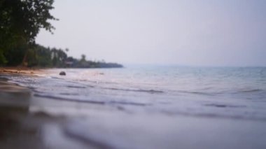 Tayland 'da gündüz vakti tropik bir plajın kumlarına akan suyu gösteren bir manzara.